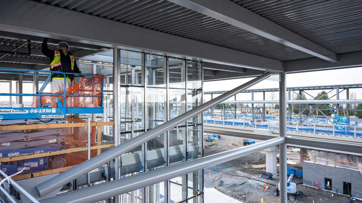 A construction worker paints a beam where the elevator will be located in the new 500-car parking garage at the Kent/Des Moines station on Wednesday, Dec. 28, 2022, in Des Moines, Wash.