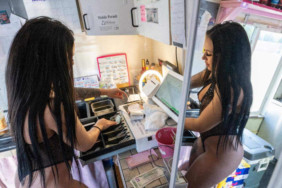 Barista Jayla Mason gets change for a customer after preparing their drink at bikini barista stand Pink Sugar Espresso on Wednesday, April 16, 2025, in Tacoma, Wash.