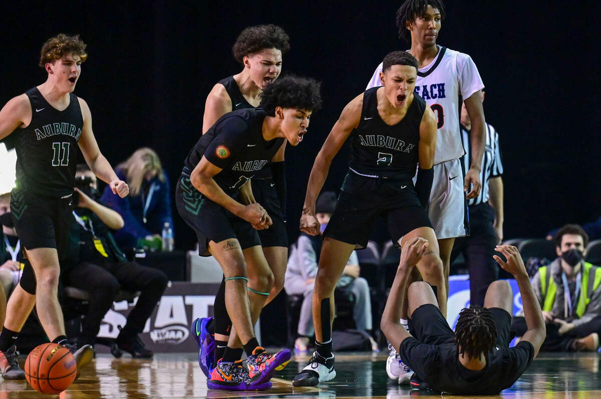 Auburn players run over to pick up guard Dae’Kwon Watson (24) after he fouled by Rainier Beach forward Jaelin Green (20) on an illegal screen in the final minutes of the fourth quarter of the Class 3A championship game on Saturday, March 5, 2022, at the Tacoma Dome, in Tacoma, Wash.
