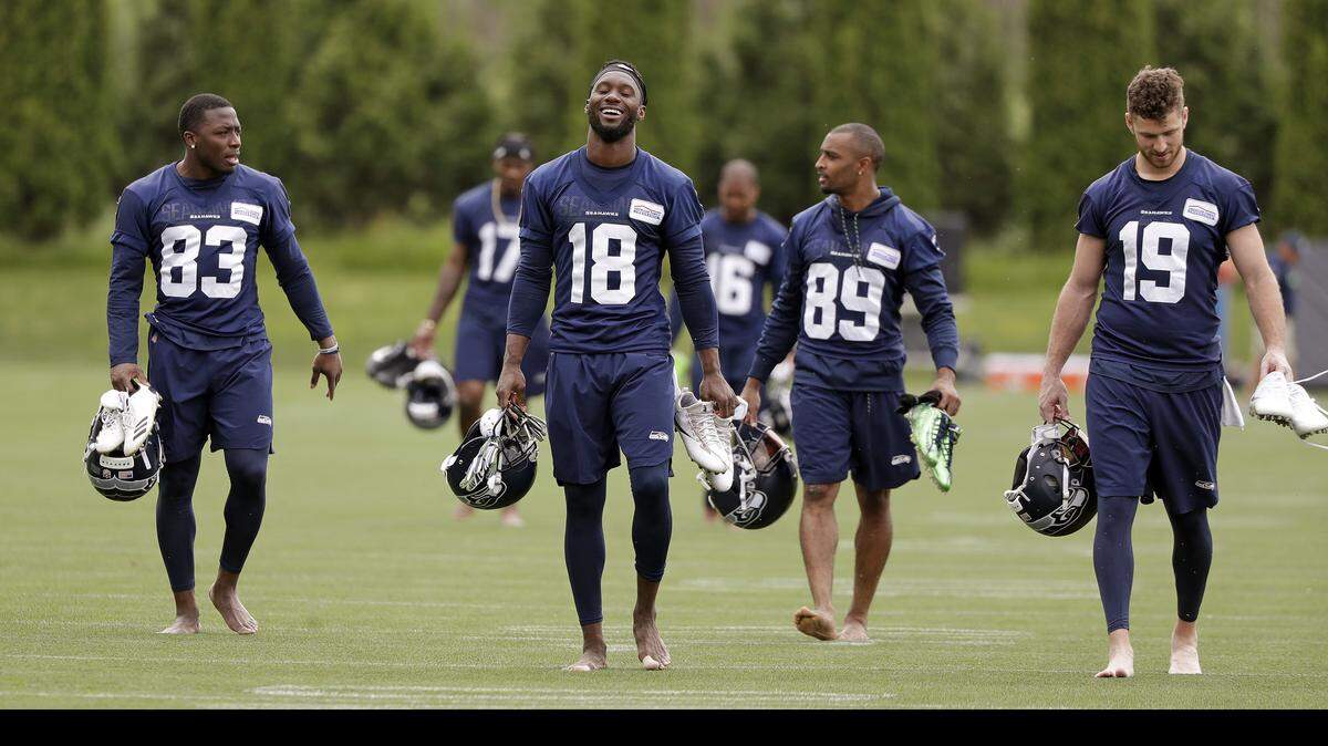 Seattle Seahawks’ David Moore (83), Jaron Brown (18), Doug Baldwin (89) and Tanner McEvoy walk barefoot off the field after the NFL football team’s practice Thursday, June 7, 2018, in Renton, Wash.