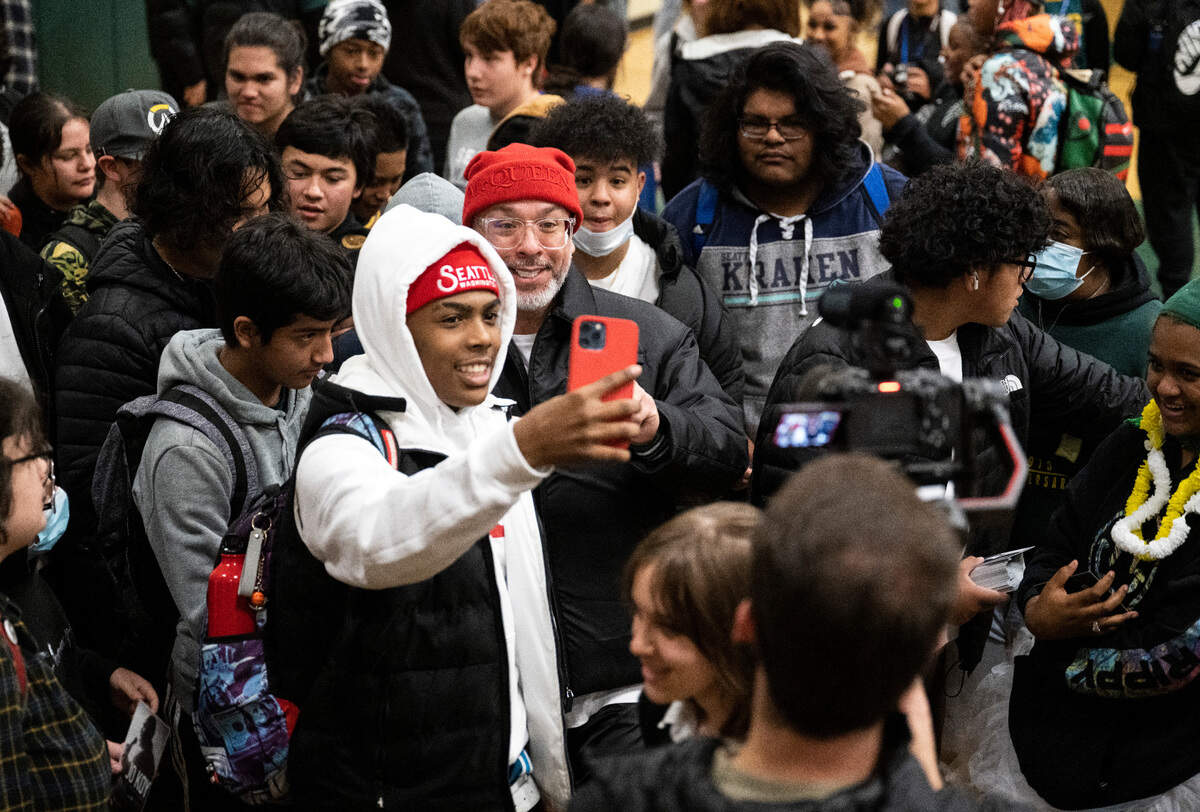 Comedian Jo Koy, right, takes a selfie with a Foss High School student at his alma mater in Tacoma, Wash. on Nov. 29, 2022. Koy presented a check for $30,000 to the Foss Scholarship Fund that will be dedicated to Foss students going into the arts. He also donated a framed poster from his movie “Easter Sunday”, a framed cover of Variety magazine and a microphone.
