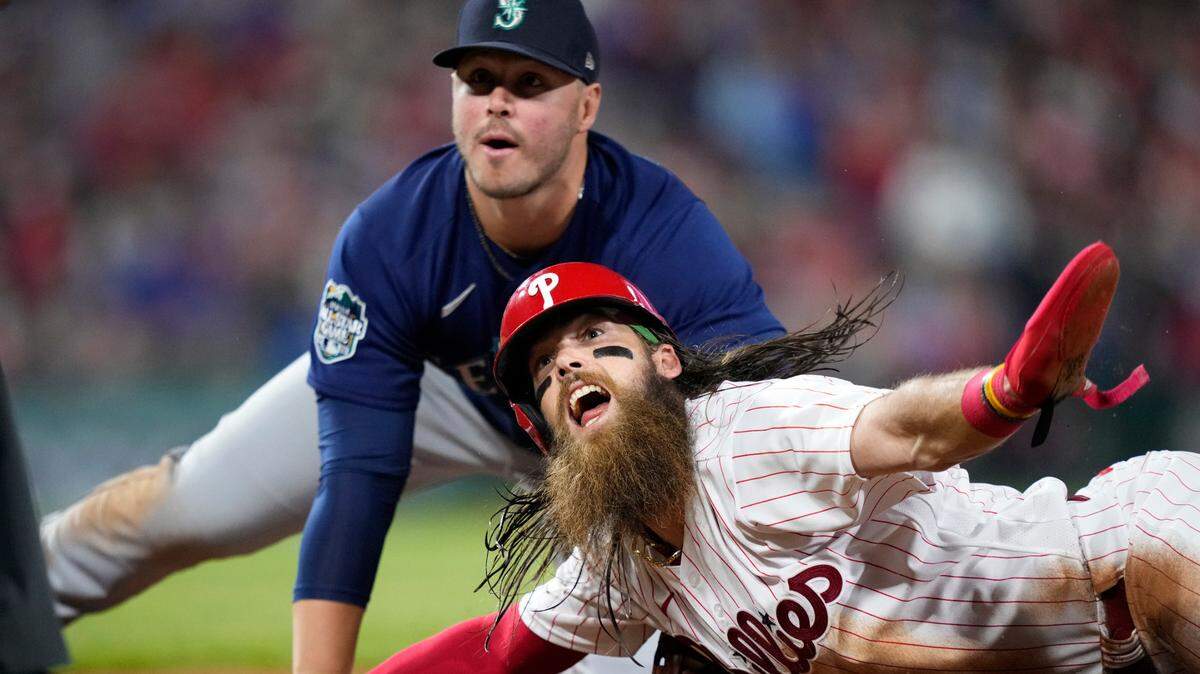 Philadelphia Phillies’ Brandon Marsh, right, reacts past Seattle Mariners first baseman Ty France after sliding back and beating a pickoff attempt during the seventh inning of a baseball game, Tuesday, April 25, 2023, in Philadelphia. (AP Photo/Matt Slocum)