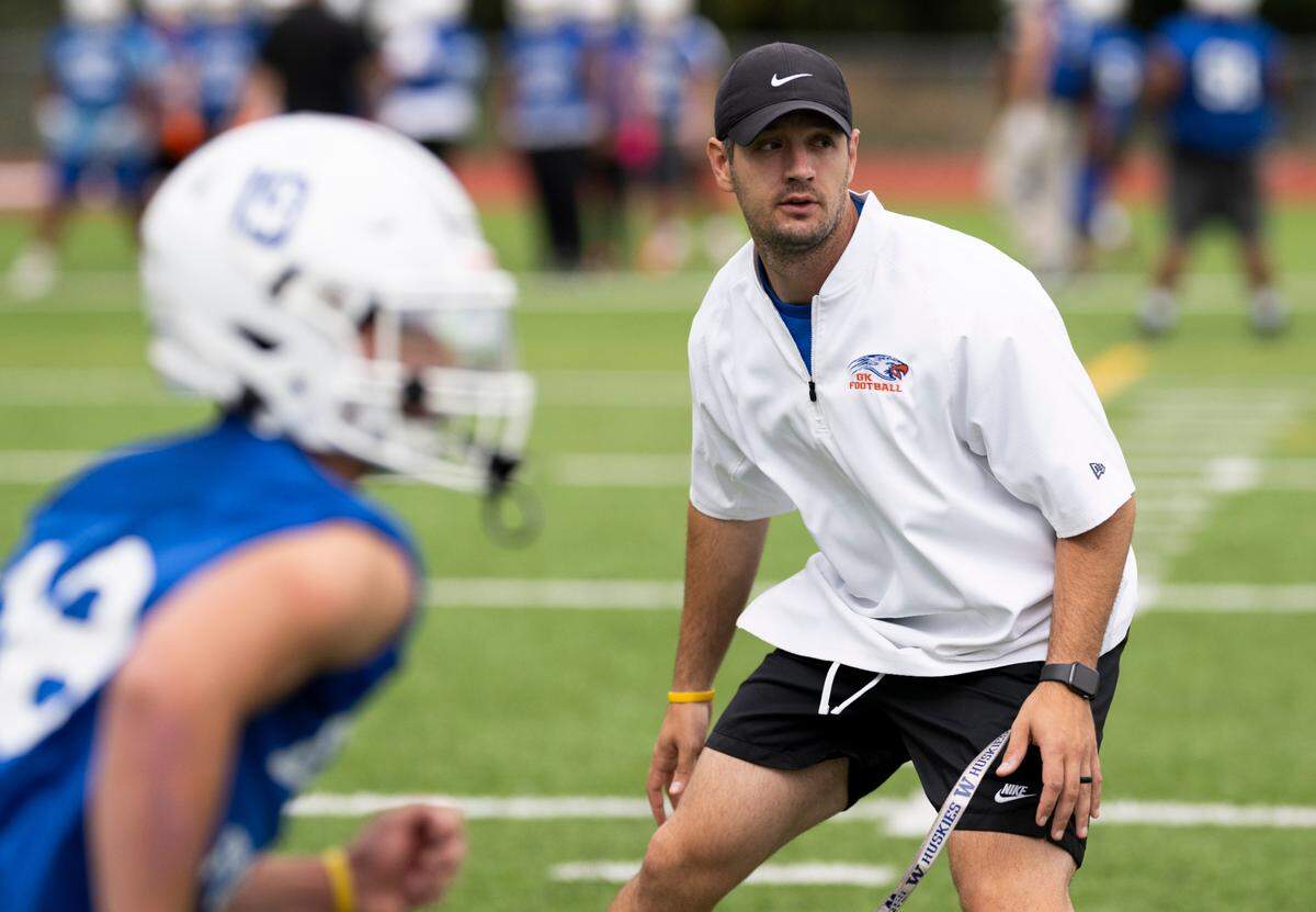 Graham-Kapowsin head coach Jeff Logan guards a receiver during a football practice at Graham-Kapowsin High School, on Thursday, Aug. 22, 2024, in Graham, Wash.