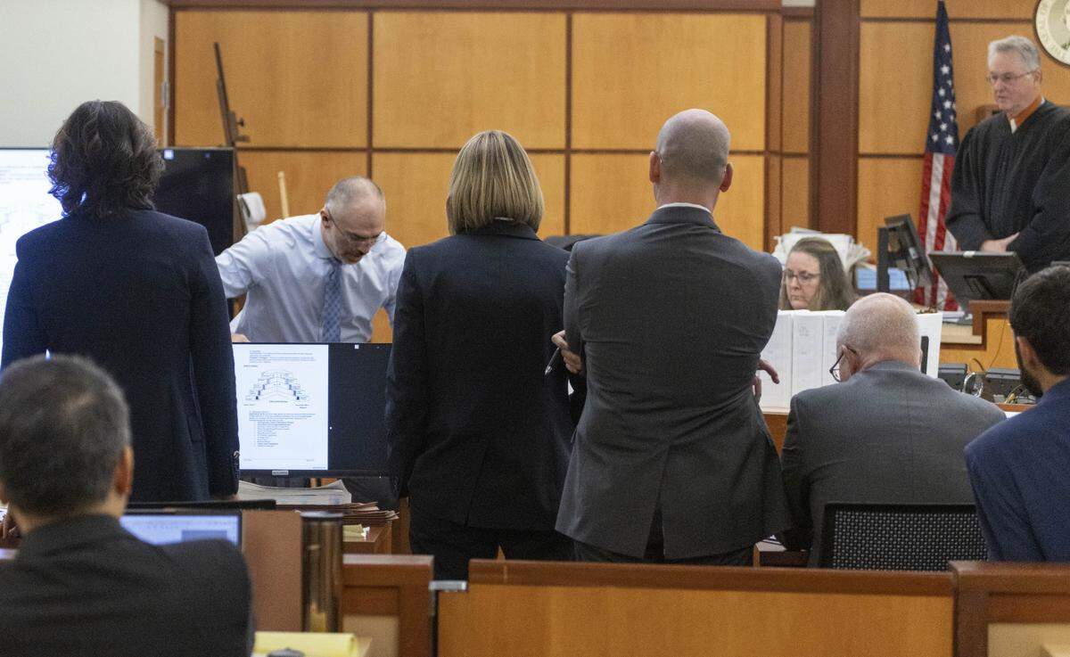 As attorneys and Pierce County Superior Court Judge Bryan Chushcoff, right, watch, Chris Nielsen, second from left, a use-of-force expert, leans over defense attorney Mark Conrad as he demonstrates to the jury how to restrain someone during the trial of three Tacoma Police officers in the killing of Manny Ellis at Pierce County Superior Court, Wednesday, Nov. 29 2023, in Tacoma, Wash.  Tacoma Police Officers Christopher Burbank, Matthew Collins and Timothy Rankine stand trial for charges related to the March 2020 killing of Manny Ellis. (Ellen M. Banner / Pool / The Seattle Times)