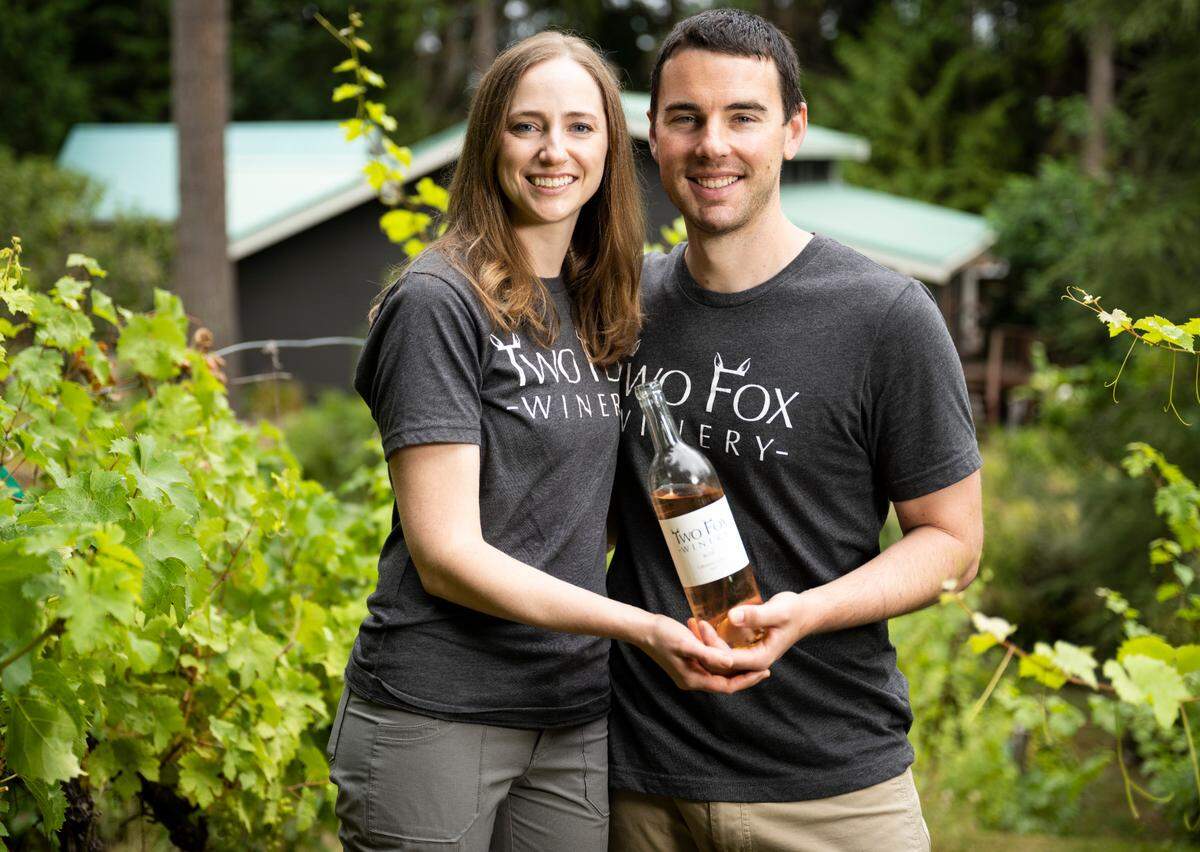 Co-owners of Two Fox Winery Tedra and Kyle Hett pose for a portrait while holding a bottle of their 2021 rose from Columbia Valley in their vineyard in Lakebay, Wash. August 26, 2022.