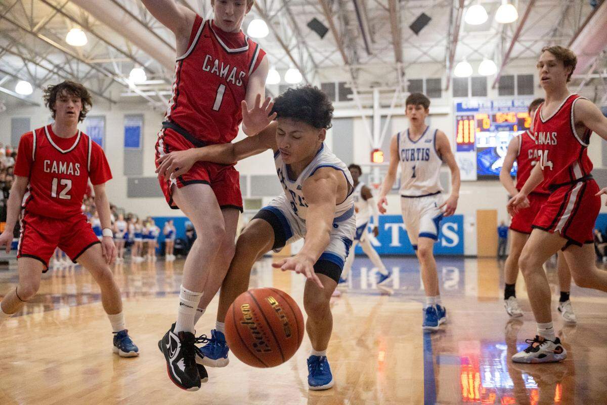 Curtis guard Devin Whitten (3) attempts to grab a loose ball before it goes out of bounds as Camas guard Beckett Currie (1) defends during the first quarter of a District 3/4 semifinal game on Thursday, Feb. 16, 2023, at Curtis High School in University Place, Wash.