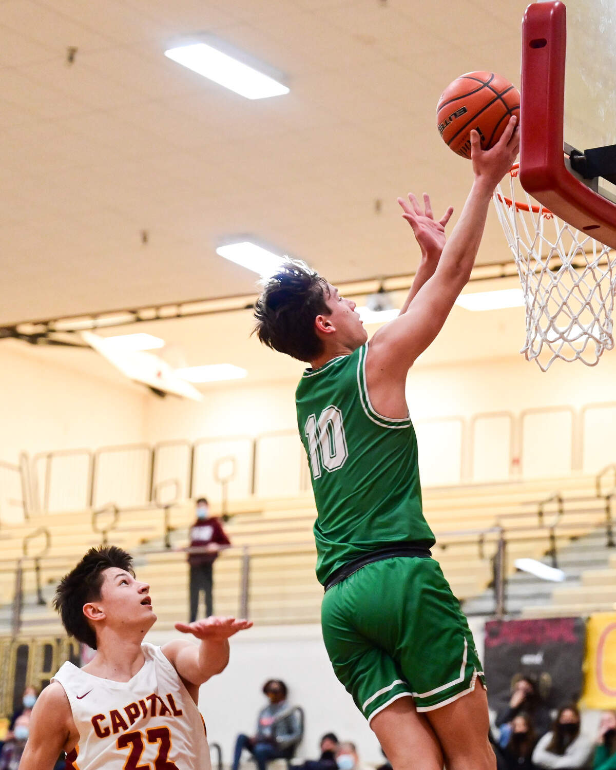 Tumwater guard Andrew Collins (10) goes in for a layup as Capital guard Carl Schreck (22) defends during the second quarter of a non-league game in Olympia on Saturday, Jan. 22, 2022.