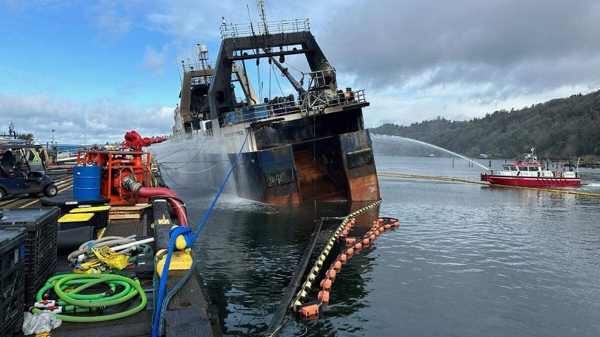 The Kodiak Enterprise can be seen listing on Tuesday as a fire boat sprays it with water.