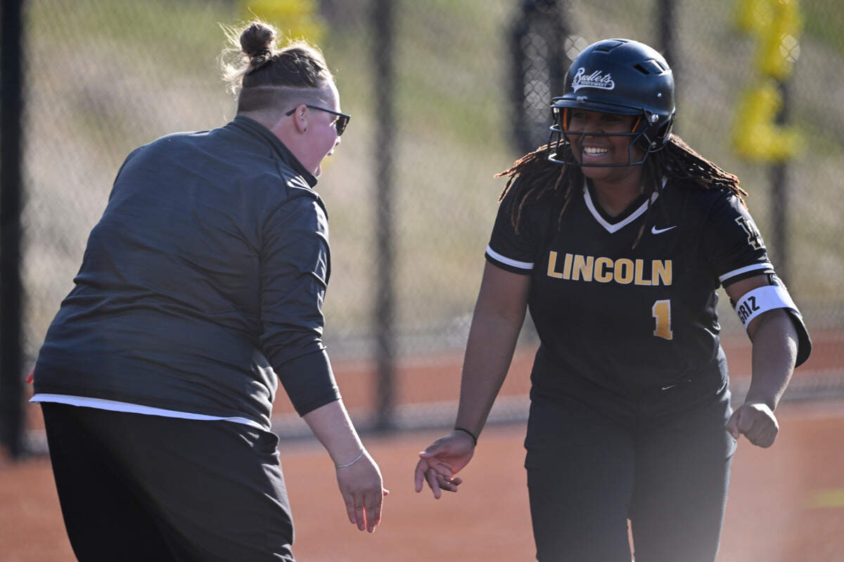 Lincoln’s Joy Wilde and head coach Haylie Tulupan high five as Wilde rounds third in her three-run home run against Lakes during the game at Lincoln High School, on Tuesday, April 30, 2024, in Tacoma, Wash.