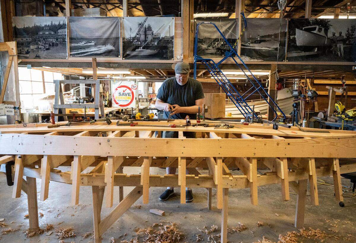 Jonathan Cunningham works on a Croatian fishing boat that is being built as part of “The Batana Project” at the Gig Harbor Boat Shop in Gig Harbor, Wash. on Wednesday, July 20, 2022. Once the boat is complete, the boat shop will host an event to reveal it Sept. 3.