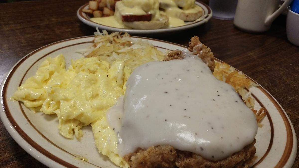 A fried pork chop breakfast in the foreground and eggs Benedict in the back. The breakfast dishes are from Tim’s Kitchen, which operates locations in Orting and South Hill.