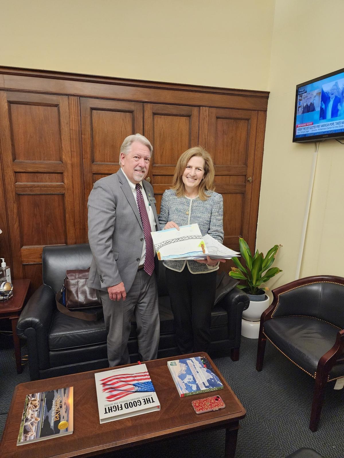 Pierce County Council member Dave Morell hands a letter to U.S. Rep. Kim Schrier on May 2, 2025. The letter is one of 100 from residents of Wilkeson and Carbonado, two towns most impacted by the closure of the Carbon River Fairfax Bridge. The Washington State Department of Transportation closed the bridge in April due to safety concerns, leaving the public with no easy way to access key areas of Mount Rainier National Park.