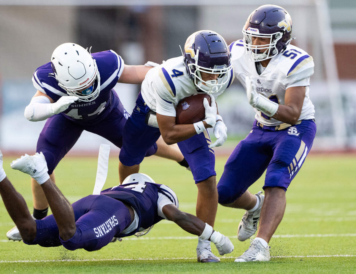 Lake Stevens’ Seth Price (4) carries the after a passes under pressure from Sumner’s Israel Nabors (14) and William Maxwell (44) during the first half of the game at Sumner High School, on Friday, Sept. 6, 2024, in Sumner, Wash.