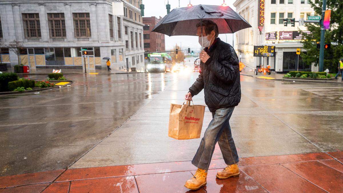 An umbrella-clad man walks across 9th Street as another wave of deluge of rain fell on downtown Tacoma on a Thursday afternoon in November 2021.