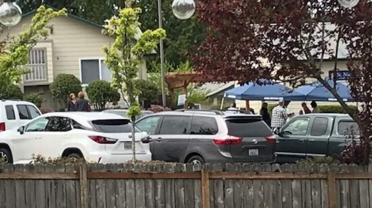 A photo taken by a neighbor shows people gathering in groups under awnings in the parking lot of St. Nicholas Church on April 28.