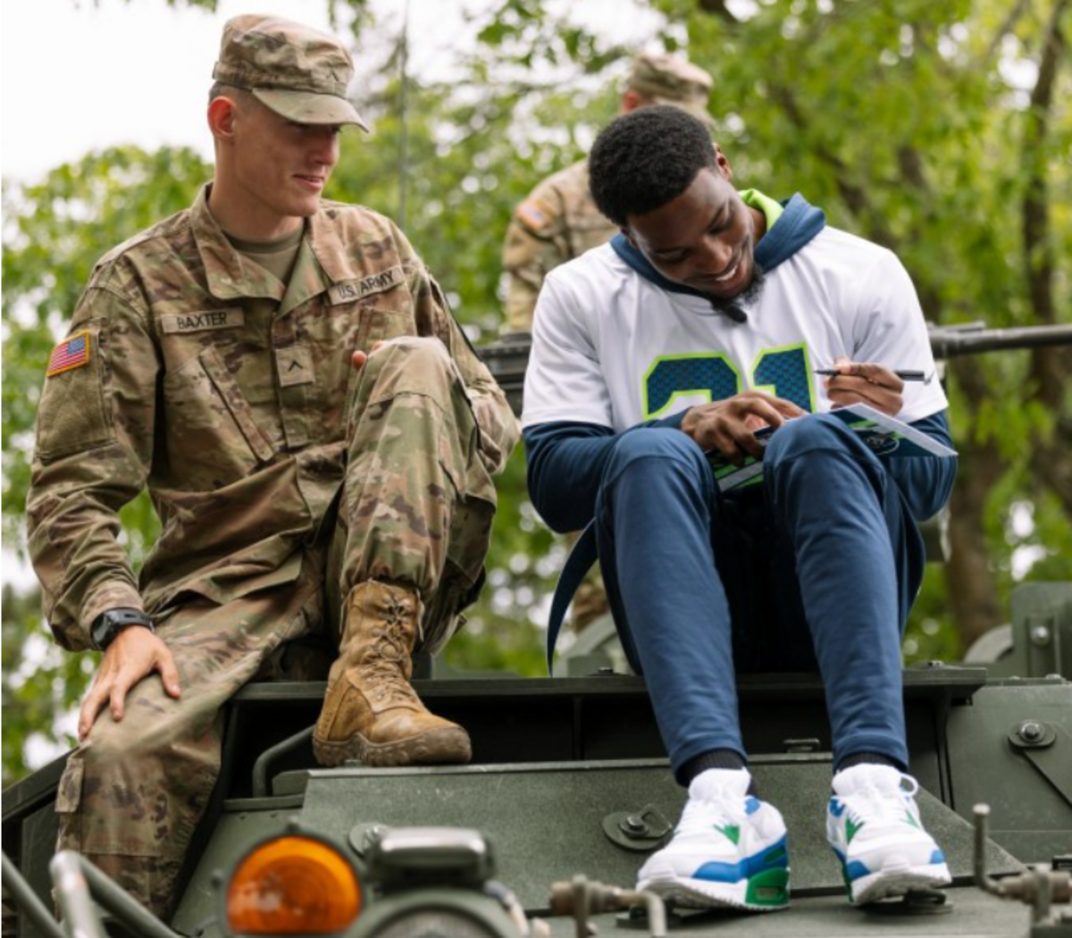 Pro Bowl cornerback Devon Witherspoon visiting with a soldier from the 1-2 Stryker Brigade Combat Team during a Seattle Seahawks visit to Joint Base Lewis-McChord in the spring of 2024.