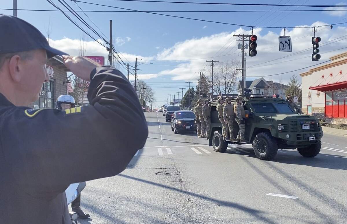Sgt. Mark Eakes of the Lakewood Police Department salutes as members of the Pierce County Sheriff’s Department SWAT team escort the body of slain deputy Dominique “Dom” Calata to the Pierce County Medical Examiner’s office Saturday. Eakes was at the South 38th Street and Pacific Avenue intersection.
