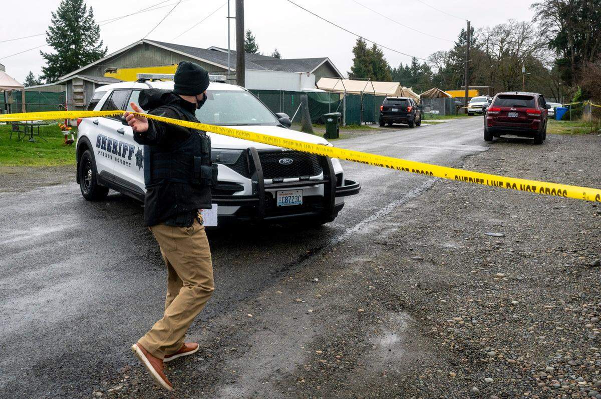 A Pierce County Sheriff’s Office Deputy underneath crime-scene tape as he heads toward a home in the 100 block of 165th Street East in Spanaway on Thursday morning. Deputies were investigating a shooting earlier in the morning that left one person dead.