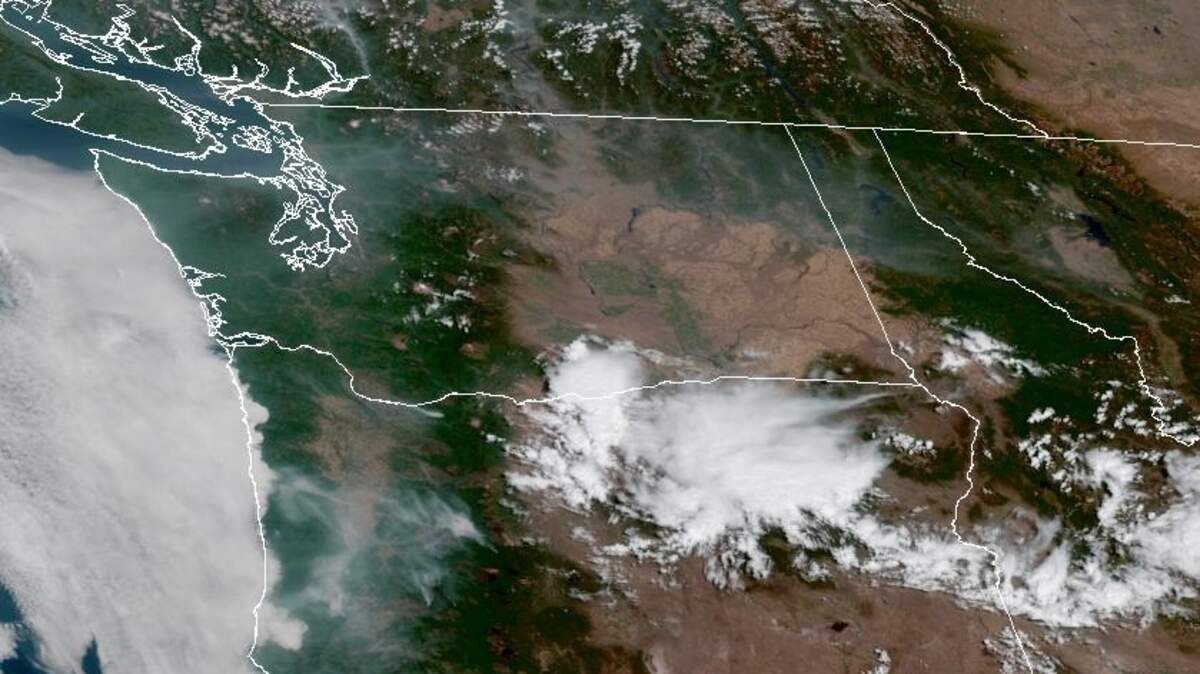 A GOES-West satellite image shows smoke drifting across western Washington and a storm system brewing off shore Saturday.
