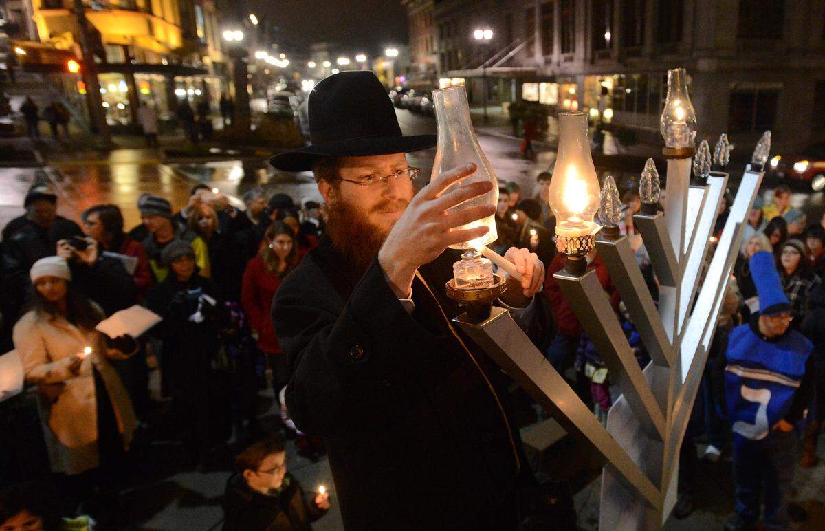 Rabbi Zalman Heber lights a menorah during a Hanukkah celebration at South 9th Street and Broadway in Tacoma on Dec. 9, 2012.