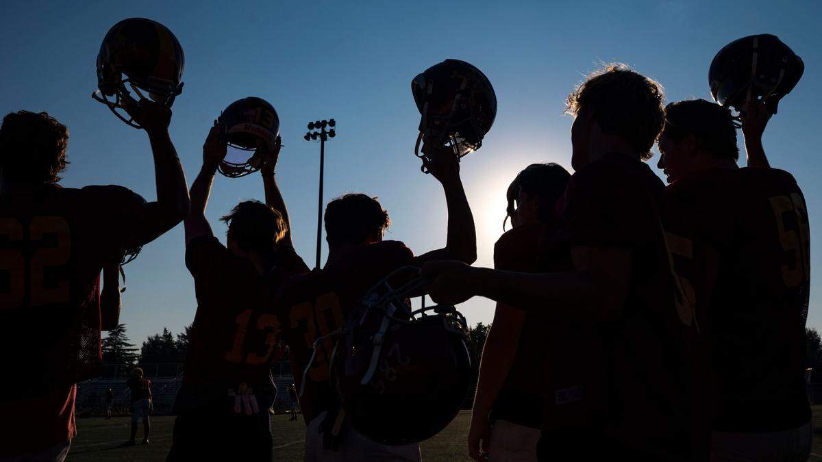 Enumclaw players raise their helmets during kick-offs while special teams run drills on Wednesday, Aug. 24, 2022, in Enumclaw, Wash.