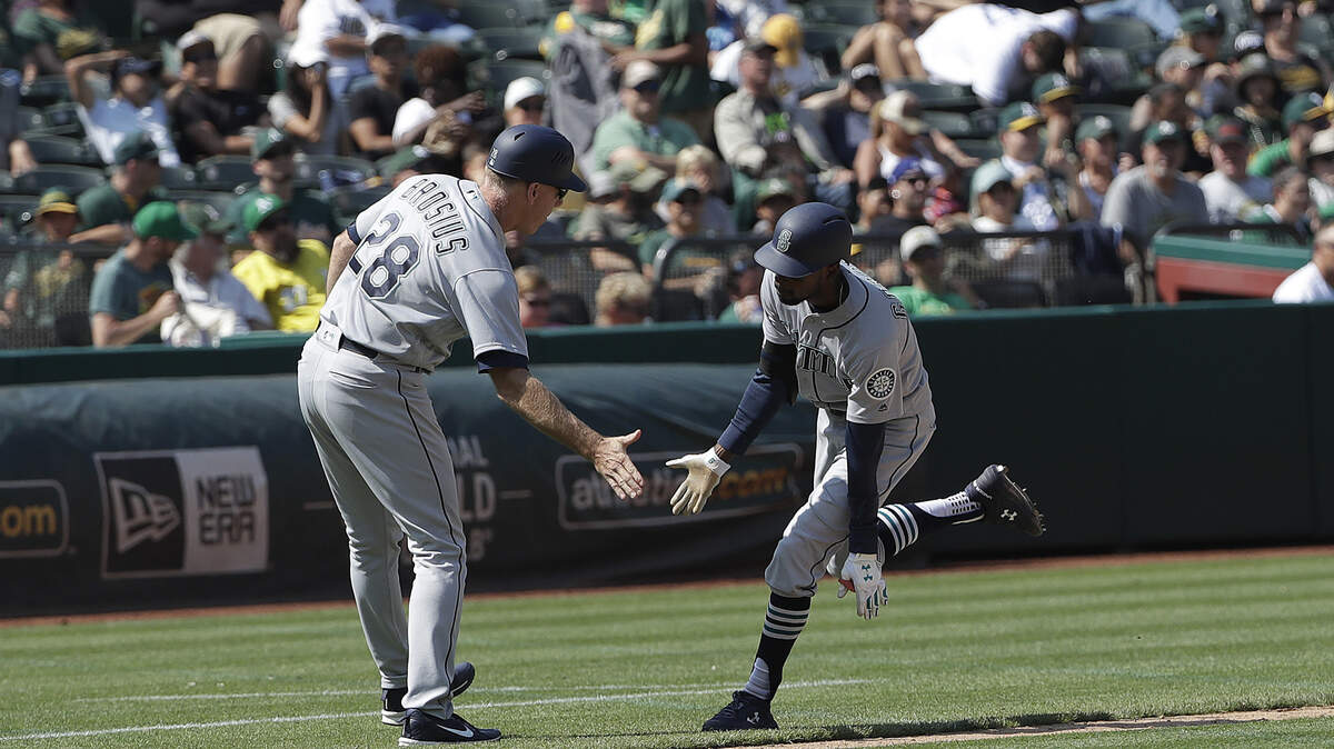 Seattle Mariners’ Dee Gordon, right, celebrates with third base coach Scott Brosius after hitting a two-run home run against the Oakland Athletics during the twelfth inning of a baseball game in Oakland, Calif., Wednesday, Aug. 15, 2018. (AP Photo/Jeff Chiu)