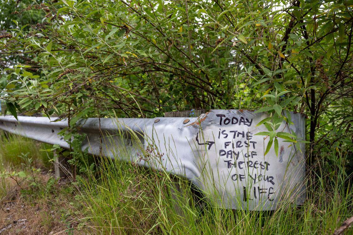 Writing on a guard rail along South Tyler Street shimmers in the morning sunlight as a homeless encampment along the road is cleared on Tuesday, May 30, 2023, in Tacoma, Wash.