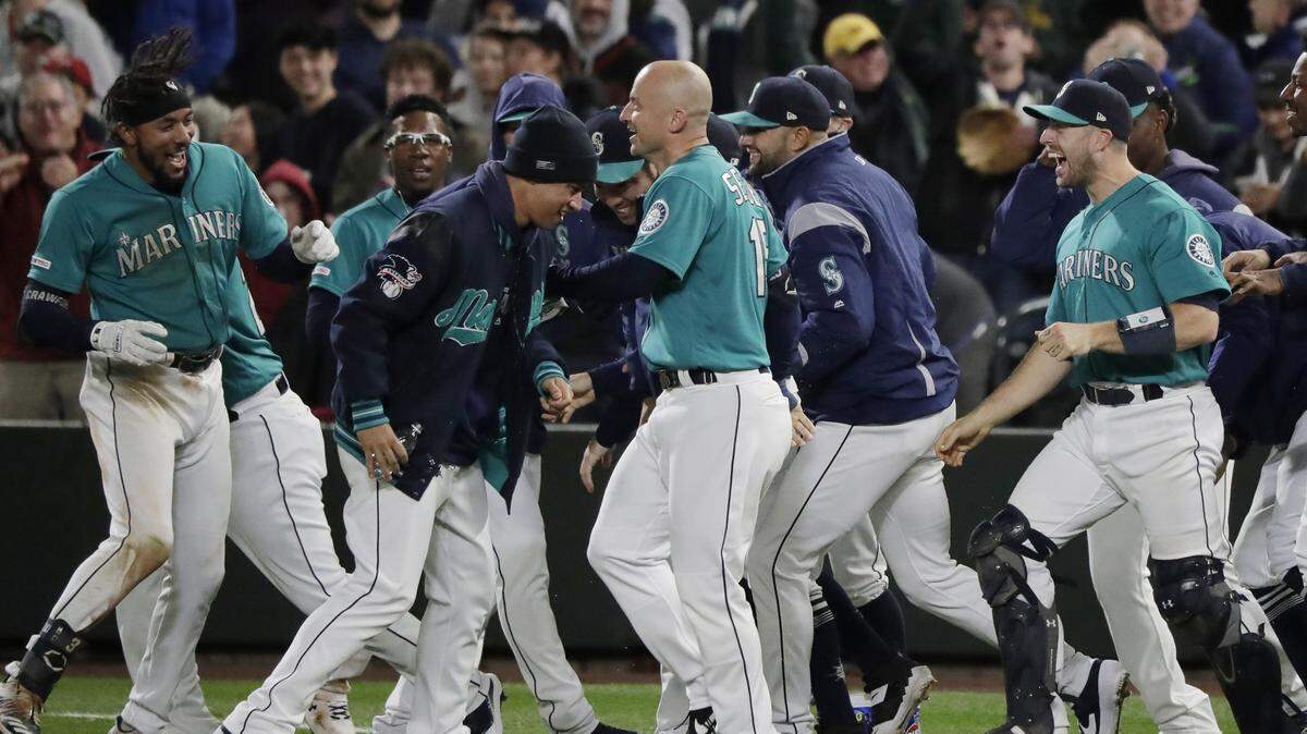 Seattle Mariners’ J.P. Crawford, left, is greeted by teammates after he hit a walk-off RBI double in the ninth inning against the Oakland Athletics to score Shed Long and give the Mariners a 4-3 win over the Oakland Athletics in a baseball game, Friday, Sept. 27, 2019, in Seattle. 