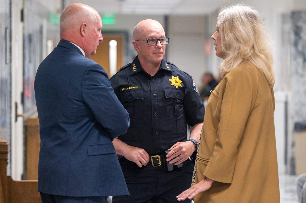 Defense attorney Brett Purtzer, from left, Pierce County Sheriff Keith Swank, and Joan Mell talk in the hallway during a brief recess in a hearing for a civil case where Pierce County Prosecuting Attorney Mary Robnett is seeking to bar Mell from acting as Swank’s attorney on Monday, June 16, 2025, at the King County Courthouse in Seattle, Wash.