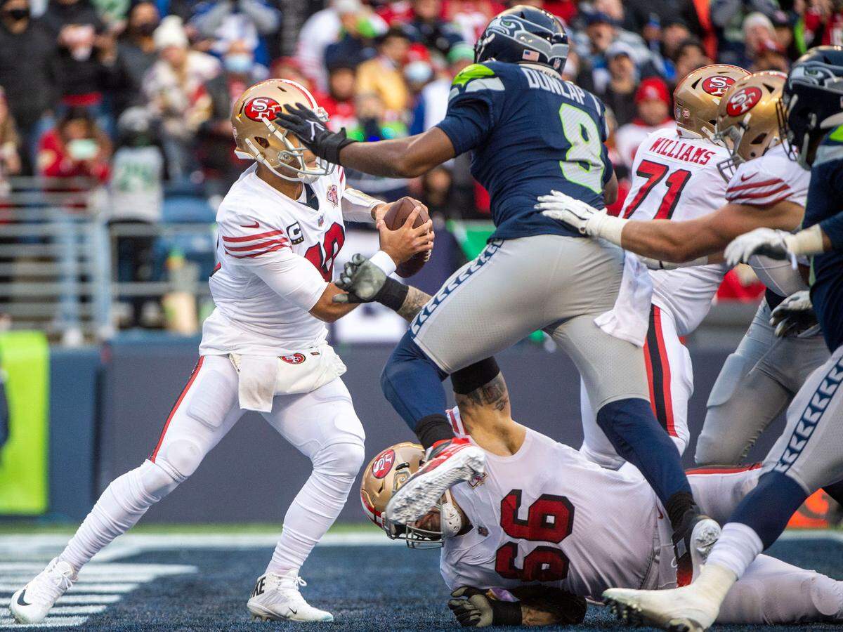 Seattle Seahawks defensive end Carlos Dunlap (8) leaps over San Francisco 49ers guard Tom Compton (66) on his way to sacking quarterback Jimmy Garoppolo (10) for a safety in the third quarter of an NFL game on Sunday at Lumen Field in Seattle.