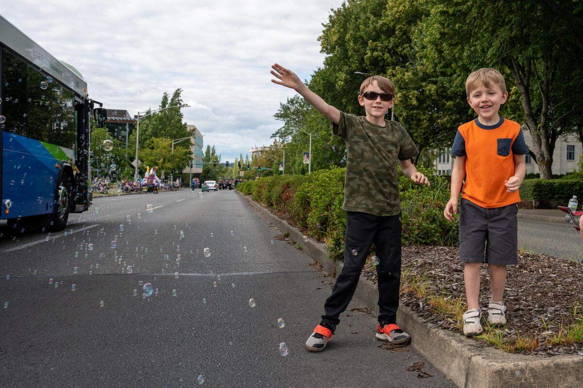 Brothers Ashton, 8, and Mason, 5, Bernard wave to the floats in the parade while trying to pop the bubbles that come their way during the Lakefair Grand Parade in Olympia, Wash. on July 16, 2022.