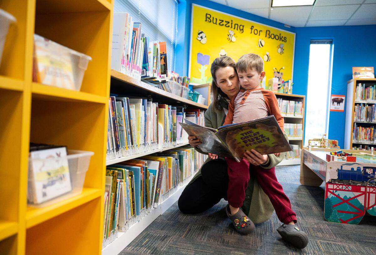 Rachel Oberg reads a book to her son, Maverick Oberg, 5, in the children’s reading area of the Sumner Public Library on Fryar Avenue in Sumner, Wash. on March 23, 2023. Sumner City Council and the Pierce County Libraries board of trustees passed resolutions to place a bond measure on the primary ballet in August that would raise funds for a new library branch.