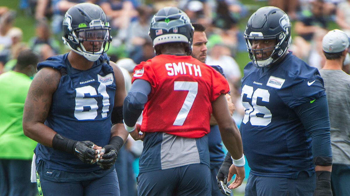 Seattle center Kyle Fuller, left, and guard Gabe Jackson discuss a formation with backup quarterback Geno Smith on the fourth day of Seahawks training camp Saturday, July 31, 2021 at the VMAC in Renton.