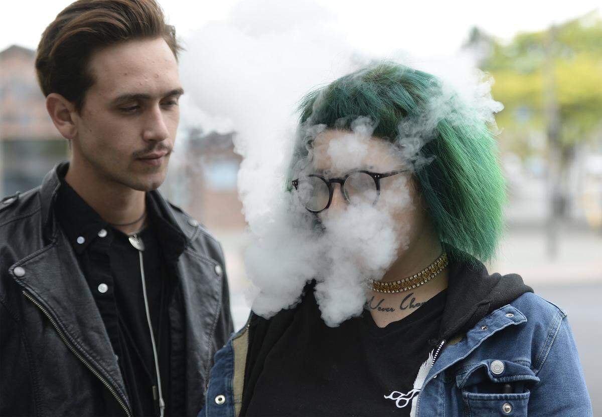 Cooper Lariviere, left, takes a break with his friend Bre Christy, who was vaping in downtown Bellingham Tuesday , Aug. 9, 2016. Christy wasn’t too concerned about a proposal before the County Council to treat vaping like smoking by banning vaping in public places. She said she already makes sure she doesn’t vape around people who are bothered by it.