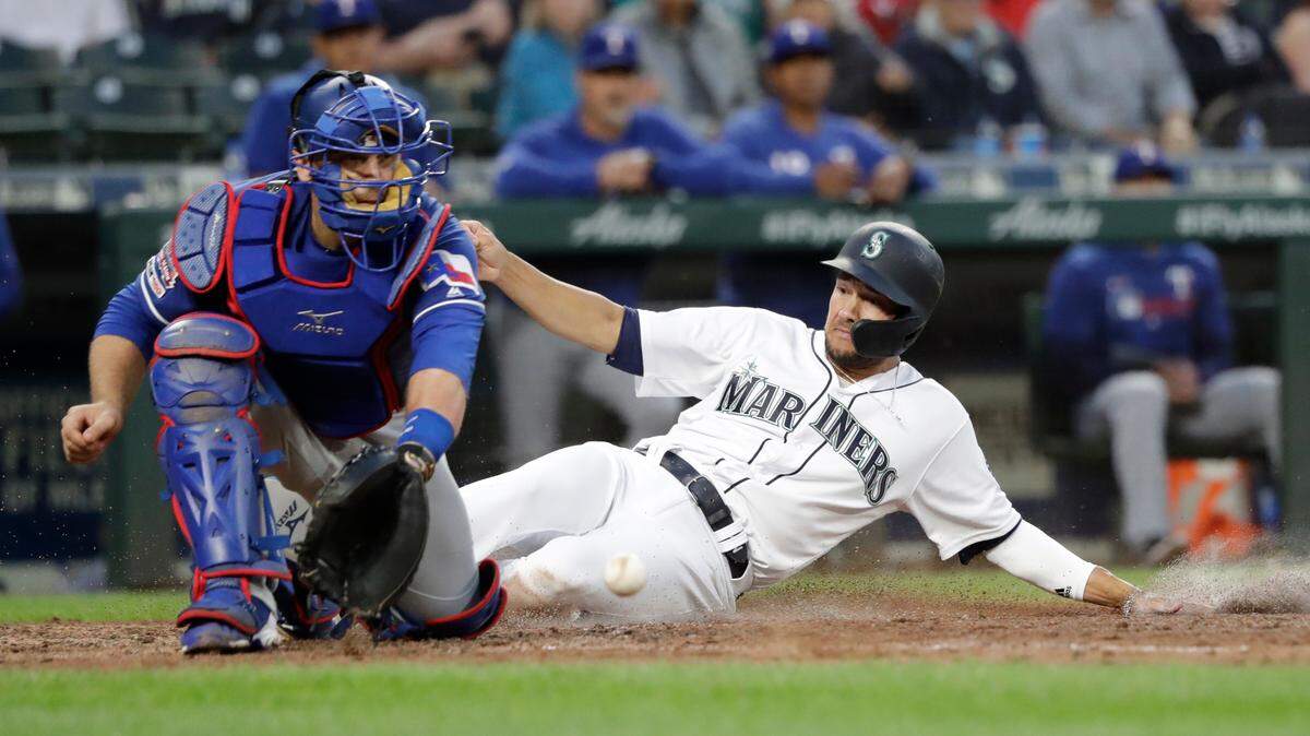 Seattle Mariners’ Kristopher Negron, right, scores as Texas Rangers catcher Tim Federowicz waits for the ball in the fifth inning of a baseball game, Tuesday, July 23, 2019, in Seattle. (AP Photo/Elaine Thompson)