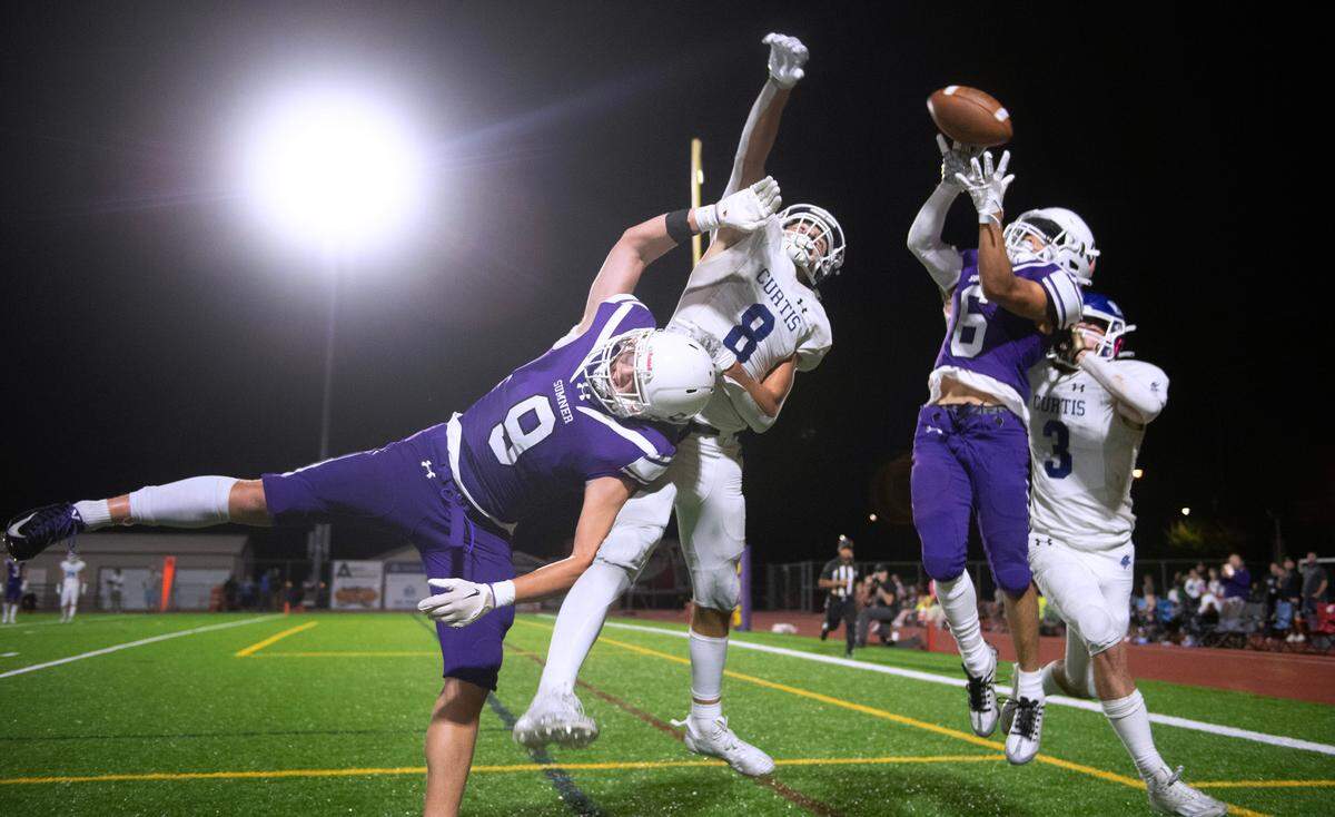 Sumner receivers Carter Cocke (9) and Maiden Ortiz (6) battle Curtis defensive backs Xavier Ahrens (8) and Parker Maddy for a pass in the end zone during Friday night’s football game at Sunset Chevy Stadium in Sumner, Washington, on Sept. 8, 2023. Curtis won the game, 38-33.