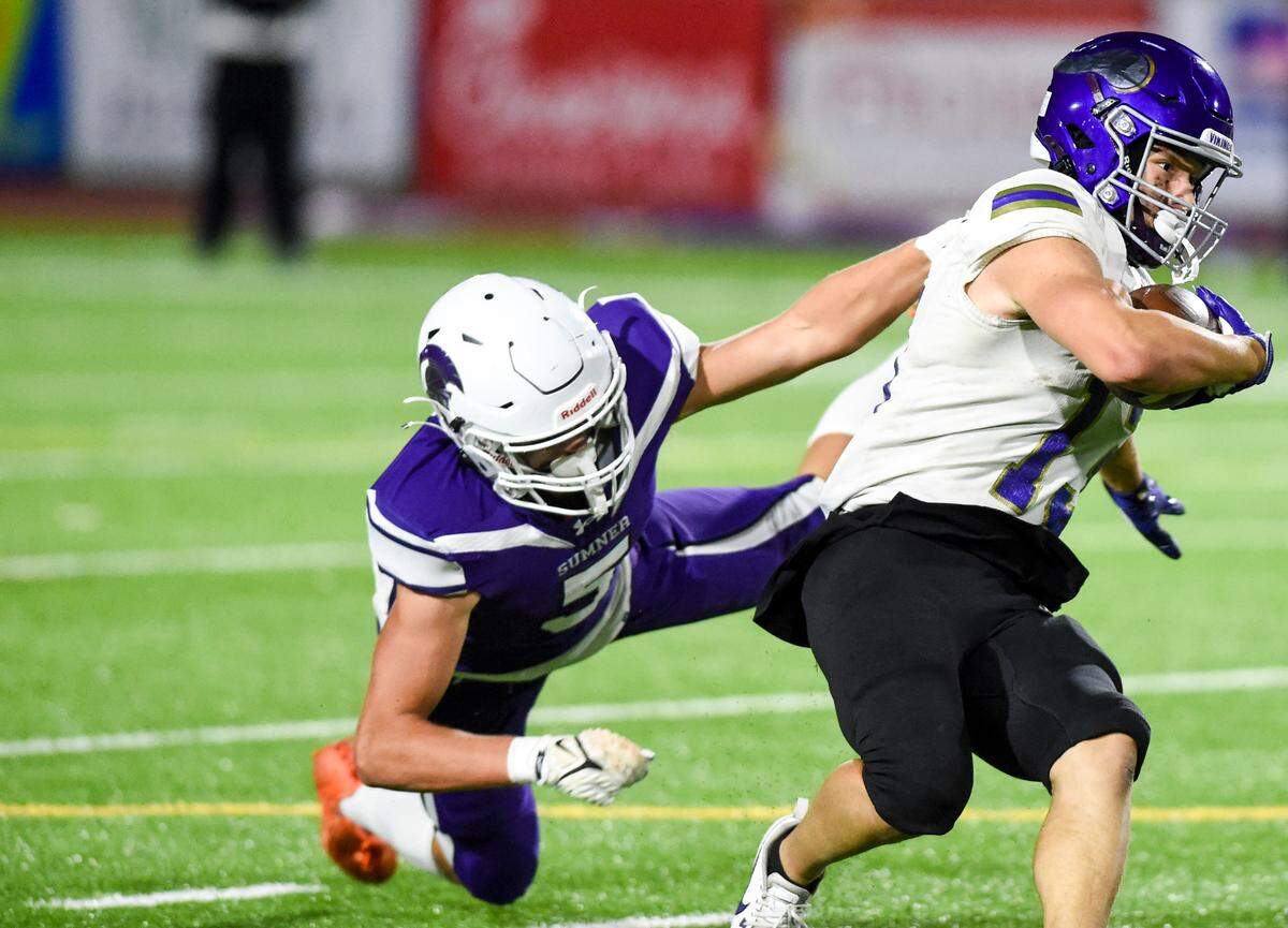 Puyallup’s Kyson Douglas (13) is dragged down by Sumner’s Cooper Miller (5) during the second half of the game at Sumner High School, Thursday, Sept. 21, 2023, Sumner, Wash.