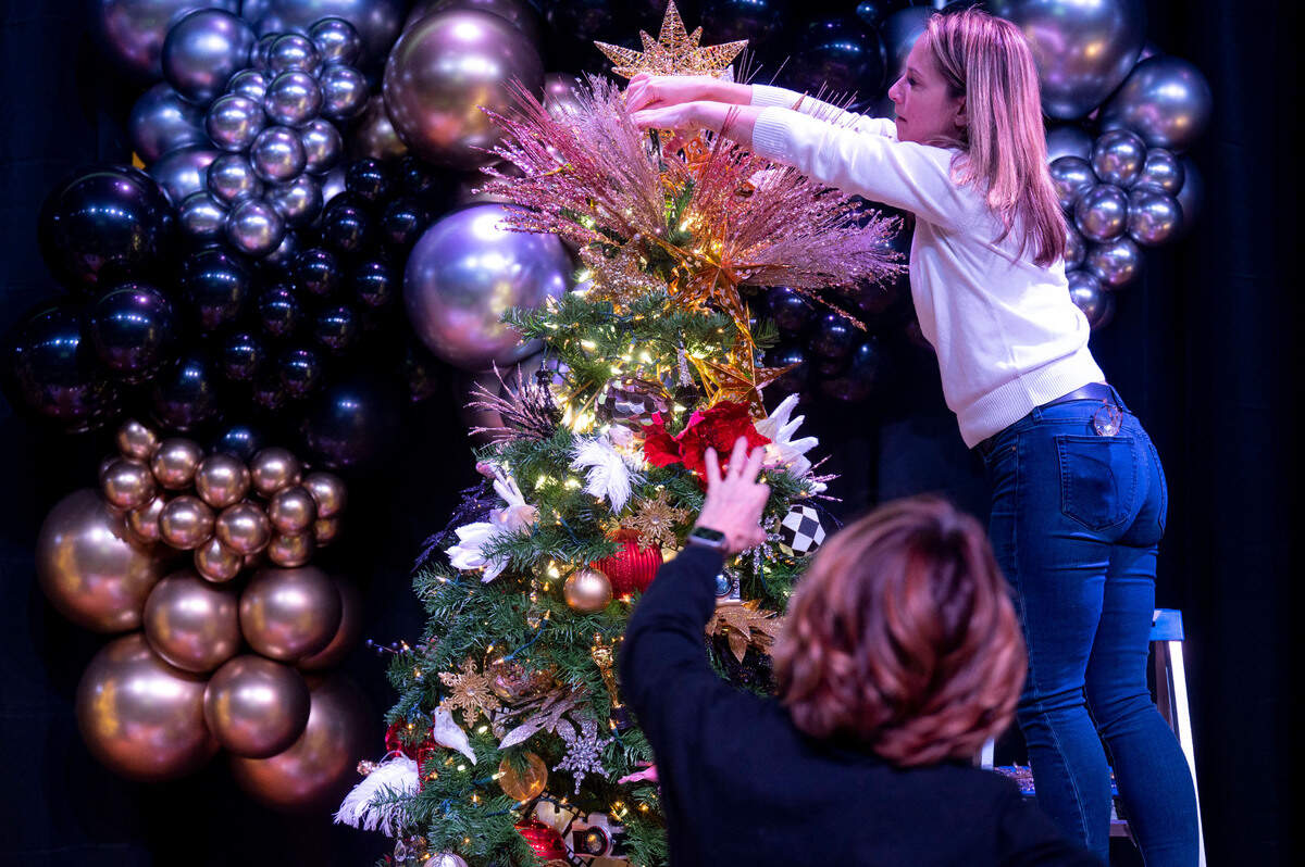 Tree decorator Tammy Hall directs Trixy Dorn of Tacoma on the positioning of ornaments atop their tree named “Starry Night” during decorating day at the Mary Bridge Children’s Festival of Trees on Tuesday, Nov. 29, 2022, at the Tacoma Armory in Tacoma.