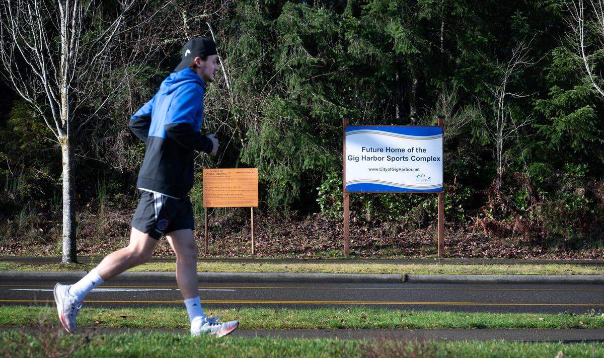 A runner passes the site of the planned Gig Harbor Sports Complex along Harbor Hill Drive on Tuesday, Dec. 26, 2023.