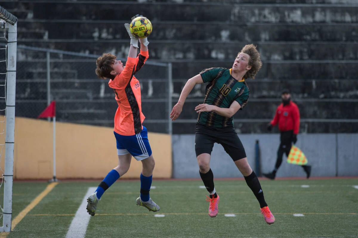 Bellevue Christian High School goalkeeper Cameron Gesell knocks the ball away in front of Vashon Island midfielder Moses Trundle-Strachan in the first half of the Class 1A West Central District championship game on Thursday, May 12, 2022 at Stadium Bowl in Tacoma, Wash.