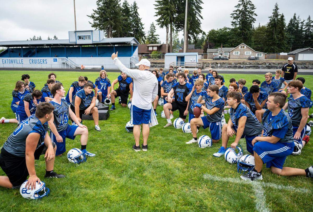 The Eatonville Cruisers varsity football team kneels while listening to their head coach Gavin Kralik talk at the end of practice at Eatonville High School in Eatonville Wash. on August 20, 2022.