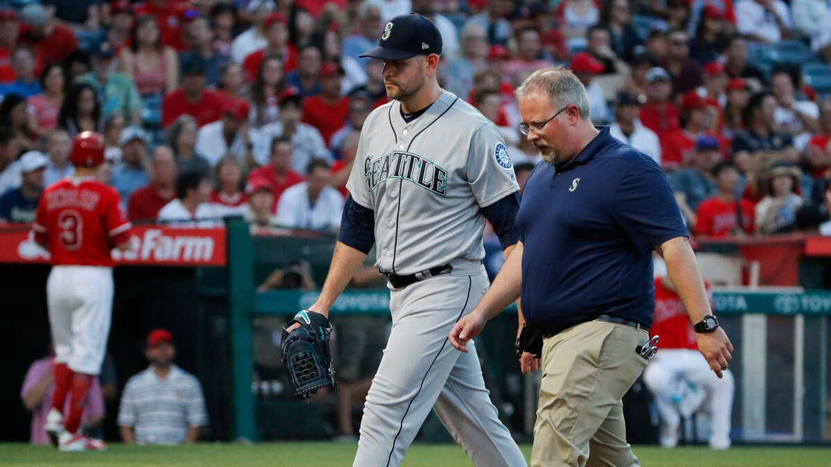 FILE - In this July 12, 2018, file photo, Seattle Mariners starting pitcher James Paxton, left, and a trainer walk off the field after Paxton was removed during the first inning of the team's baseball game against the Los Angeles Angels in Anaheim, Calif.
