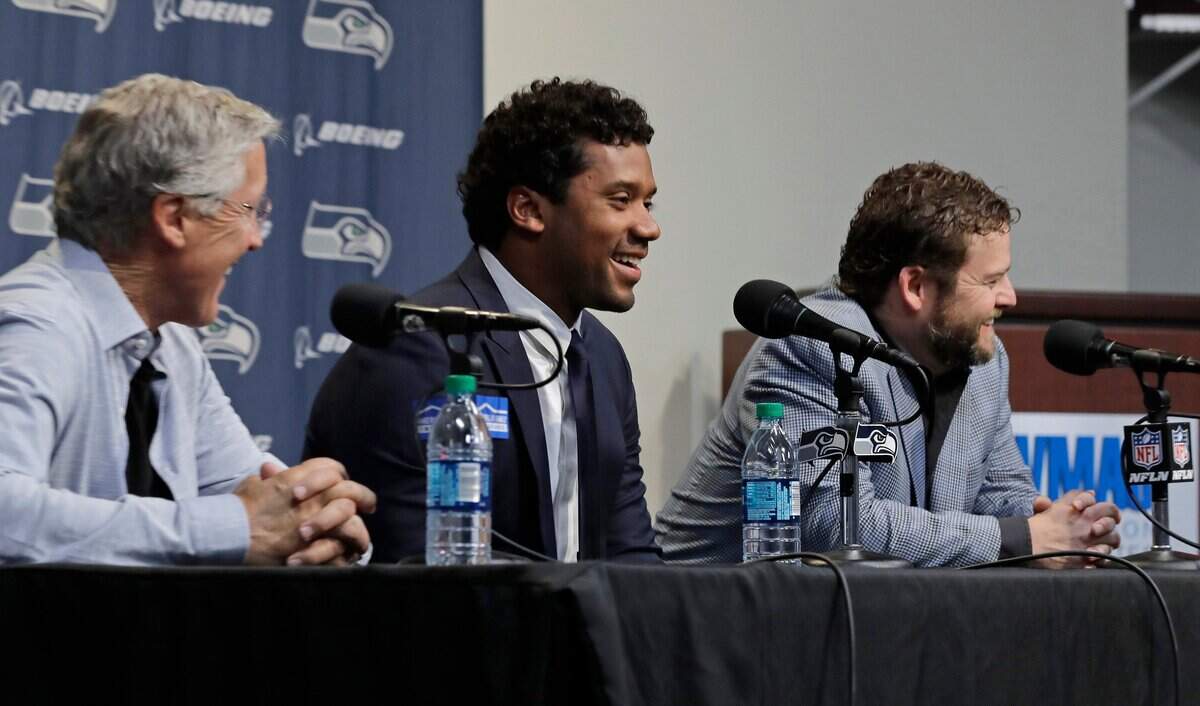 Seattle Seahawks quarterback Russell Wilson, center, talks to reporters along with coach Pete Carroll, left, and general manager John Schneider, right, Wednesday, April 17, 2019, in Renton, Wash. Earlier in the week, Wilson signed a $140 million, four-year extension with the NFL football team. (AP Photo/Ted S. Warren)
