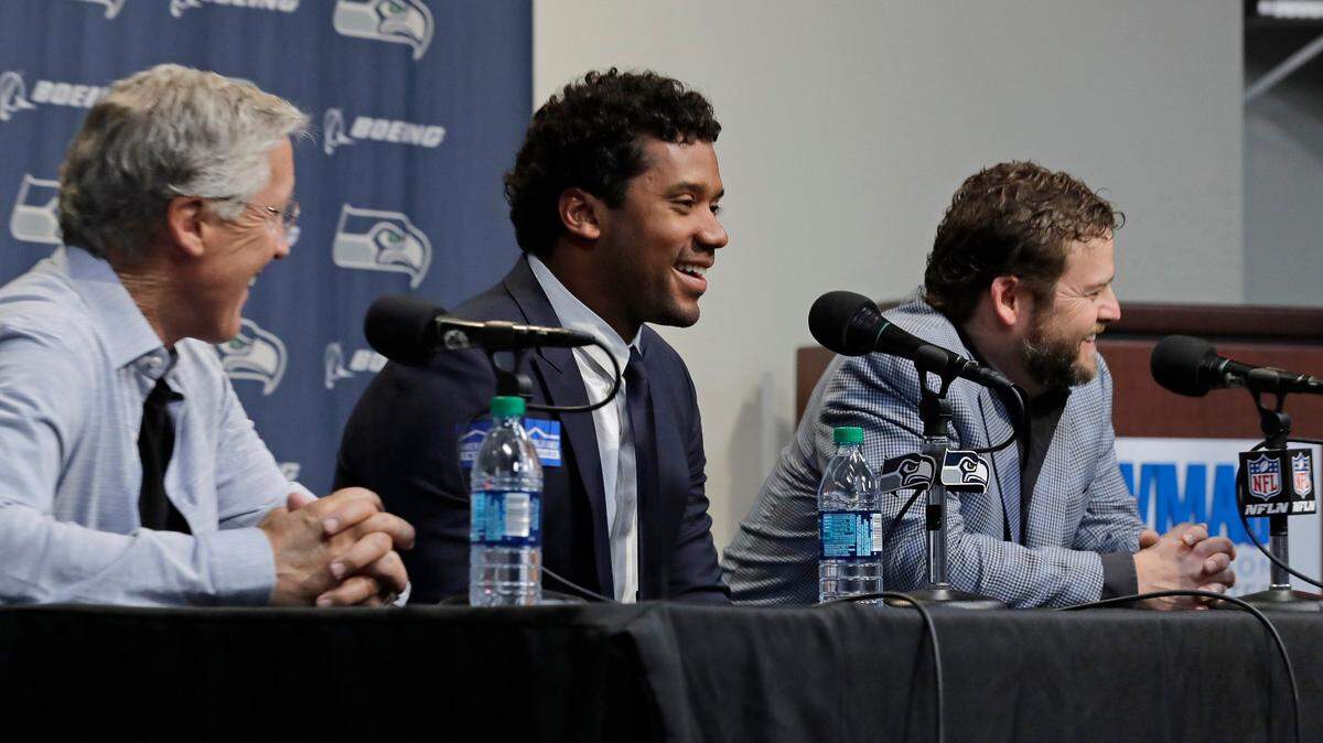 Seattle Seahawks quarterback Russell Wilson, center, talks to reporters along with coach Pete Carroll, left, and general manager John Schneider, right, Wednesday, April 17, 2019, in Renton, Wash. Earlier in the week, Wilson signed a $140 million, four-year extension with the NFL football team. (AP Photo/Ted S. Warren)