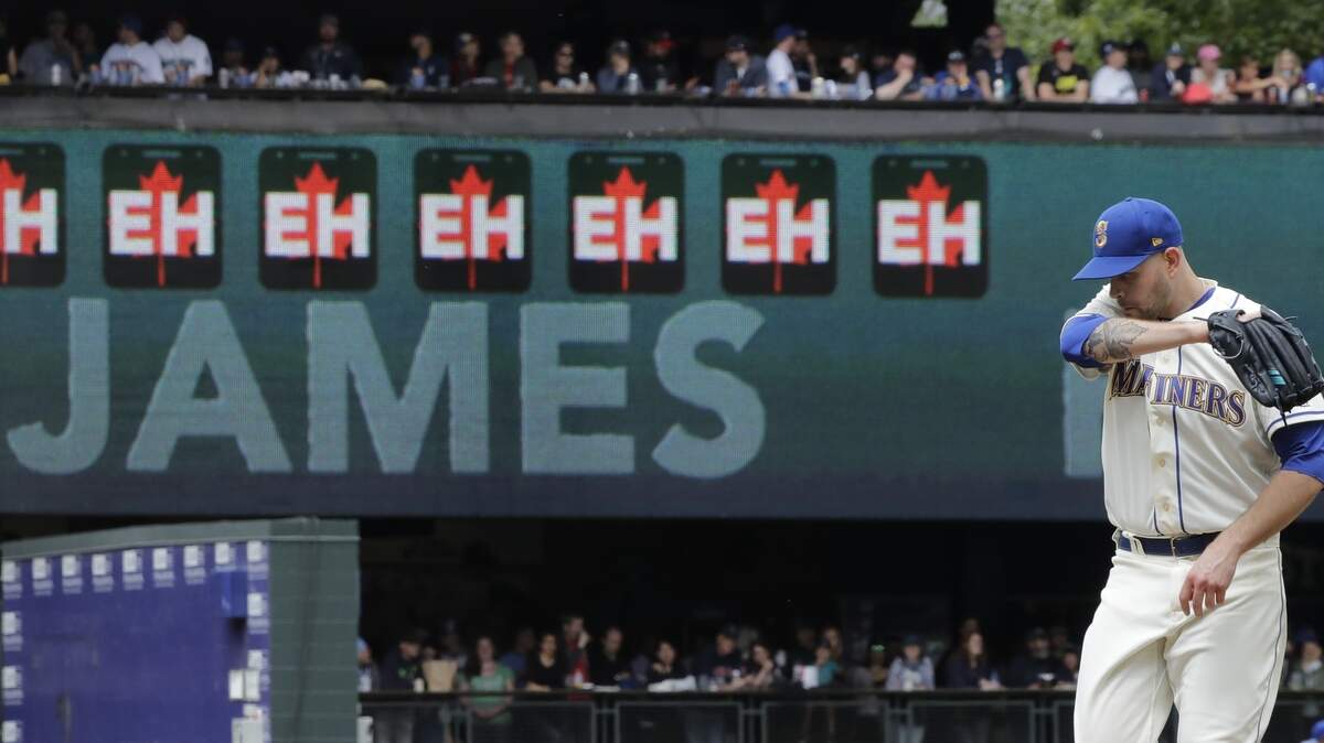 With a video display keeping track of his strikeouts with “Eh” logos, Seattle Mariners starting pitcher James Paxton stands on the mound during a baseball game against the Kansas City Royals, Sunday, July 1, 2018, in Seattle. (AP Photo/Ted S. Warren)