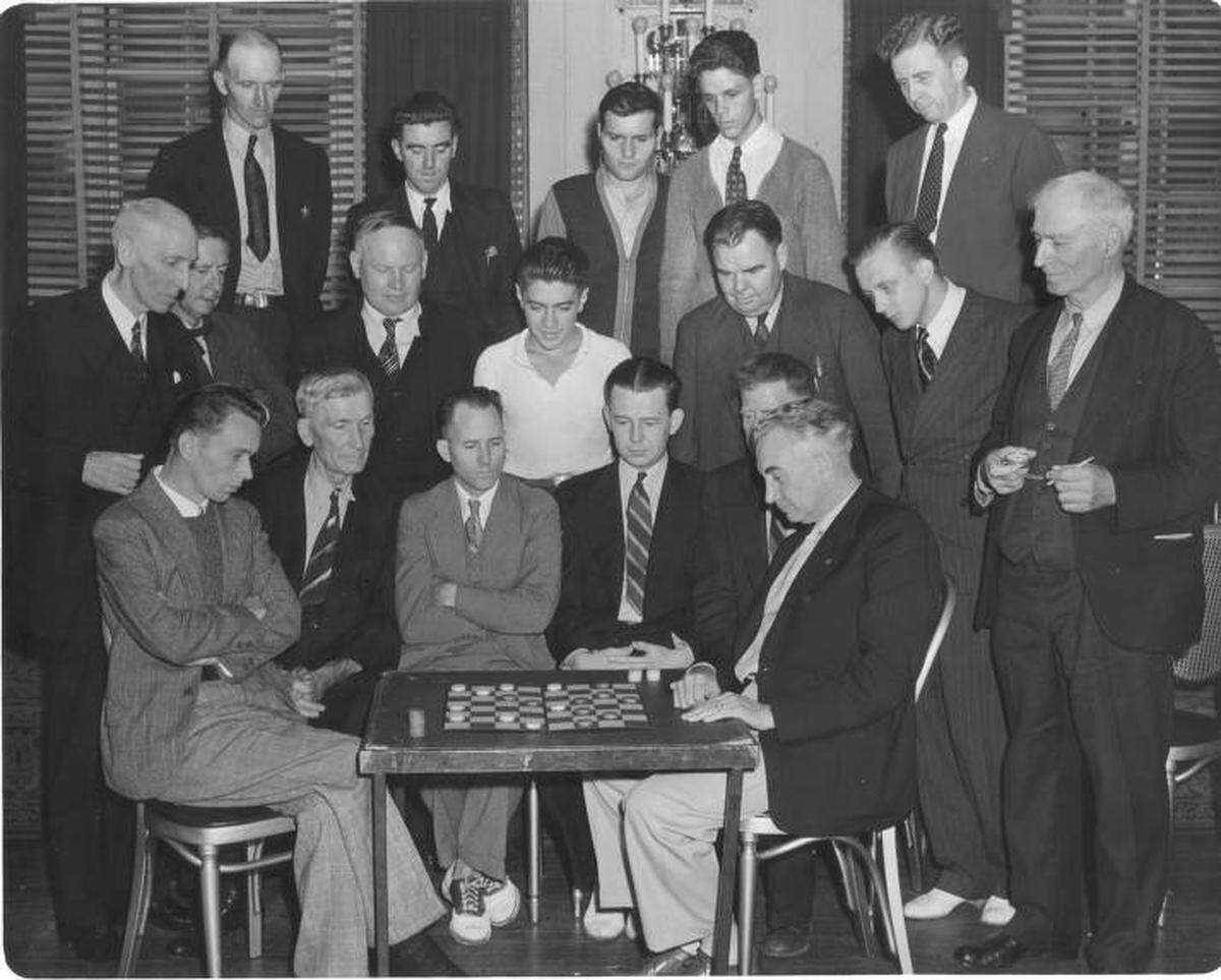 All eyes were on the board as two unidentified men faced off in the National Checker Association’s second annual title tournament at the Winthrop Hotel, August 31st, 1939. Expert players from throughout the US poured into Tacoma to be in the competition. The tournament, which began on August 28, had a record entry of 30 players. The overall winner would be awarded a new automobile, the largest prize ever offered in a checker tournament. In addition, there would be about $1500 in supplementary prizes. The man standing right has a stopwatch to time each competitor’s move.
