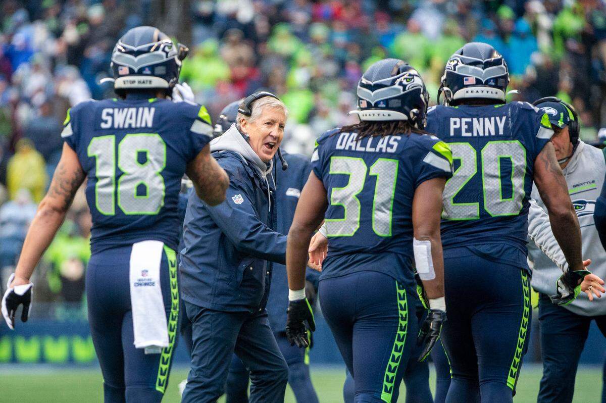 Seattle Seahawks head coach Pete Carroll smiles as he congratulates Seattle Seahawks running back Rashaad Penny (20) after he scored a touchdown in the first quarter of an NFL game on Sunday, Jan. 2, 2022, at Lumen Field in Seattle.