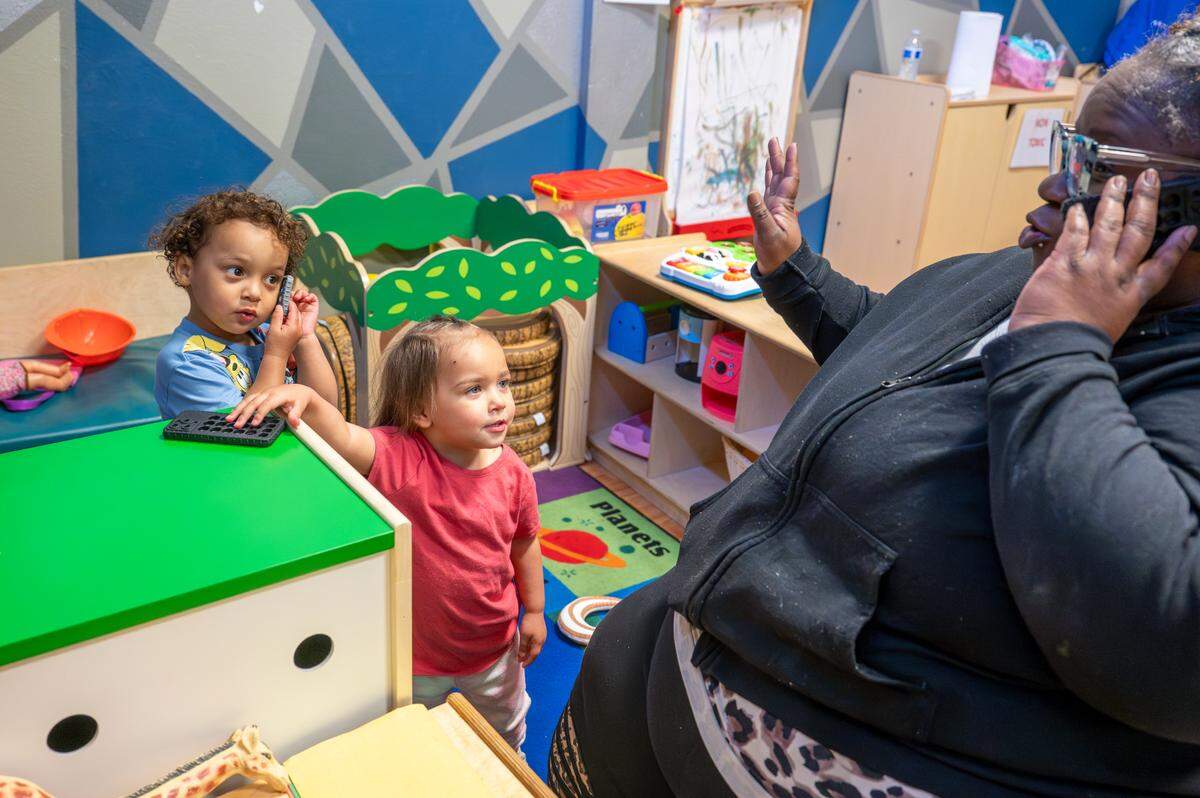 Early Head Start students Jace, 3, left, and Shaheyla, 2, center, hold an imaginary phone conversation with teacher Dairi Ray on Friday, May 9, 2025, at the Multicultural Child and Family Hope Center in Tacoma.