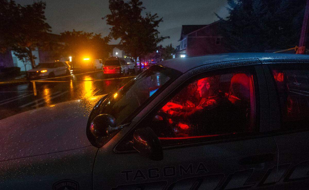 A Tacoma police officer works in his squad car while blocking access to the 4200 block of Everett Street where four people were shot and killed Thursday afternoon, Oct. 21, 2021. An investigation was ongoing and the suspect or suspects were still at large.