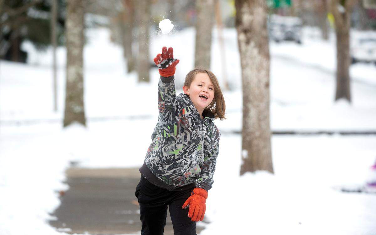 Ian Childs, 9, fires a snowball at his sister as they play in their front yard in DuPont, Washington, on Tuesday, Dec. 28, 2021.